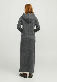 Felpa con cappuccio grigia a maglia, abbinata a una lunga gonna coordinata. Tessuto morbido e design aderente, caratterizzato da un aspetto semplice e minimalista.
