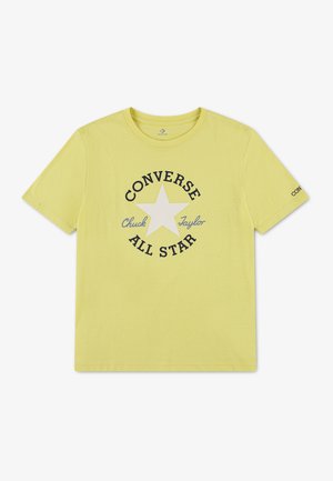 T-shirt jaune à manches courtes avec une étoile blanche et un texte noir indiquant "Converse All Star Chuck Taylor" centré sur le devant.