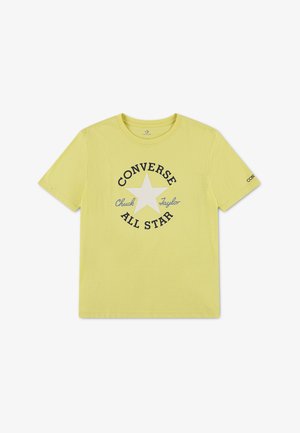 Gele T-shirt met korte mouwen met een witte ster en zwarte tekst "Converse All Star Chuck Taylor" in het midden aan de voorkant.