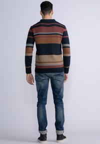 Gebreide trui met horizontale strepen in marineblauw, roest, beige en grijs. Heeft een ronde hals en geribbelde manchetten en zoom. In combinatie met blauwe jeans.