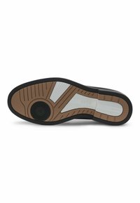 Suola di una scarpa in marrone, nero e bianco, caratterizzata da una superficie in gomma testurizzata e motivi rigati per una migliore aderenza. Dettaglio circolare centrale.