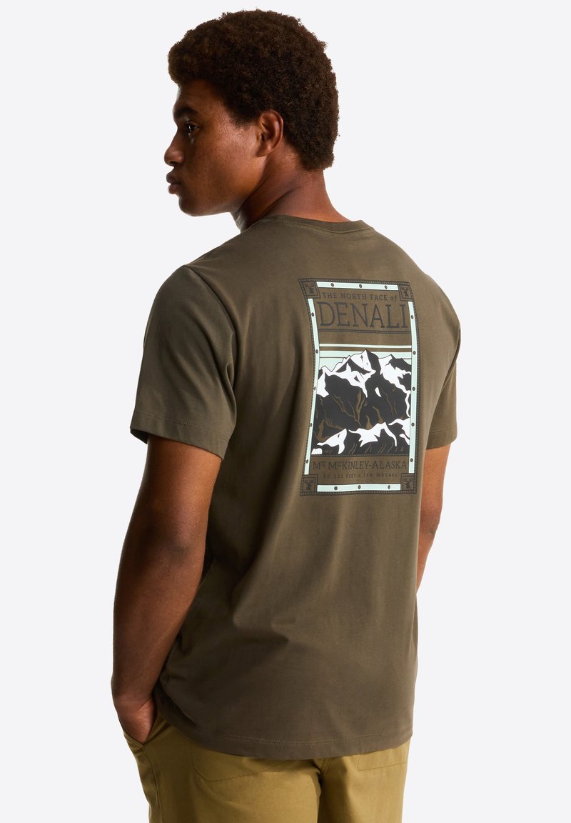 Olive green cotton t-shirt featuring a graphic design of mountains. Text includes "DENALI" and "MT. McKinley, Alaska," with bordered accents.