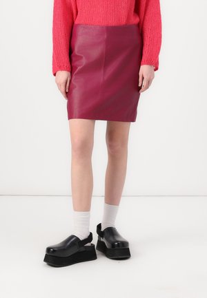 Fuksia skinn mini skjørt med en glatt tekstur, sammen med kraftige svarte plattformsko og hvite ankelstrømper. Strikket rosa genser over.