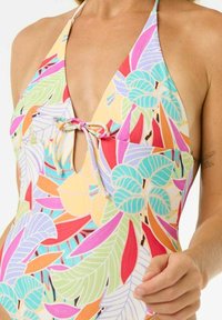Maillot de bain une pièce coloré avec un col halter, présentant un motif de feuilles florales dans des teintes vives de rose, vert, orange et jaune.