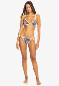Bikini a motivo bianco e nero con top a triangolo e slip con laccetti. Realizzato in tessuto morbido con copertura minima e spalline regolabili.