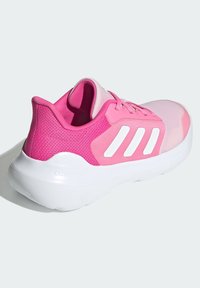 Różowy but sportowy z siateczkową cholewką, gładkimi pastelowymi akcentami, białym logo w postaci trzech pasków oraz wygodną białą podeszwą oznaczoną "CLOUDFOAM."