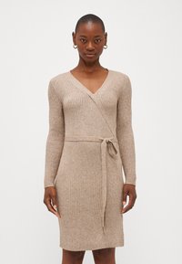 Beige strikket kjole med ribbet tekstur, V-hals, lange ermer og beltedetalj i midjen, som faller til over kneet.