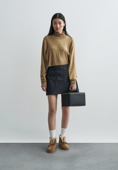 Bežs turtlenecks, džinsu mini svārki, krēma zeķes, brūni potīšu zābaki ar kažoku apmalēm un melna ģeometriska raksta somiņa.