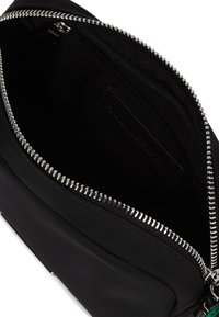 Borsa di tessuto nera con zip argentata aperta, che mostra una piccola tasca interna con zip e fodera nera all'interno.