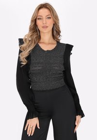Top lung cu mâneci lungi, de culoare negru și argintiu, cu detalii din volane, corp texturat, decolteu zimțat și manșete elastice, asortat cu pantaloni negri.