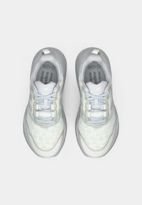 Lichtgrijze sportchoenen met een gestructureerd bovenwerk, witte accenten en een gevoerde zool. Bevat een vetersluiting en een logo op de tong.
