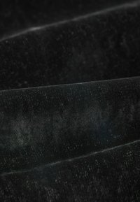 Černý sametový materiál s jemnou texturou a subtilním leskem. Povrch má hladký, bohatý vzhled s jemnými záhyby.