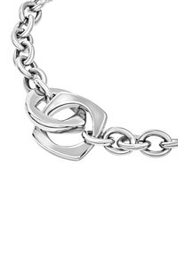 Zblízka na leštěný stříbrný řetěz se dvěma propletenými, nepravidelně tvarovanými geometrickými články na bílém pozadí.