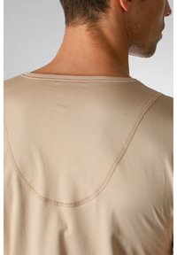 Beżowa bawełniana koszulka z okrągłym dekoltem, z widocznymi detalami przeszycia i gładką teksturą, uchwycona z tyłu.