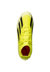 Zapatilla de fútbol amarilla brillante con rayas negras, parte superior texturada y un acento rojo en la suela. Cuenta con cierre de cordones y un diseño elegante.