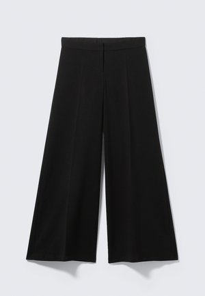 Pantalon noir à jambes larges en tissu doux, avec une taille haute, des plis à l'avant, sans éléments métalliques visibles ni motifs.