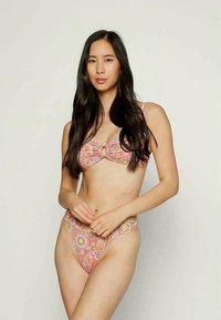 Bikini szett több színű virágmintával. A felsőrész gyűrűdísszel rendelkezik, míg az alsórész egyező mintázatú és oldalán gyűrűs részletek találhatók.