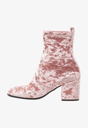 Stivaletti alla caviglia in velluto rosa con punta quadrata e tacco blocco. La texture è morbida e soffice, con una tomaia liscia che presenta lievi variazioni.