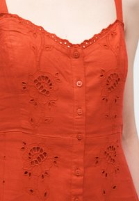 Αμάνικο φορέμα σε καμένο πορτοκαλί με κεντήματα λουλουδιών, εμπρόσθιο κουμπωτό και λαιμόκοψη με δαντέλα.