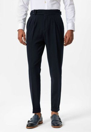 Navy trousers made of lightweight fabric, featuring pleats, side pockets, and a buckle detail at the waist. Rolled cuffs complete the look.