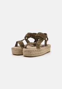 Brune semskede plattformsandaler med kryssede stropper, metalløye-detaljer og en vevd jute-lignende såle, med en hevet hæl.