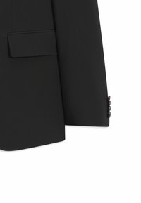 Manche d'une veste de costume noire avec quatre boutons sur le poignet et une poche à rabat sur la partie inférieure avant de la veste.