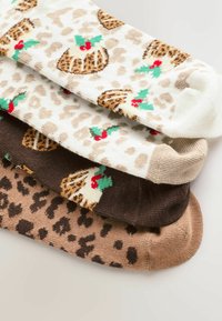 Four pairs of socks featuring holiday patterns: cream with puddings and green leaves, brown leopard print, and two shades of tan.