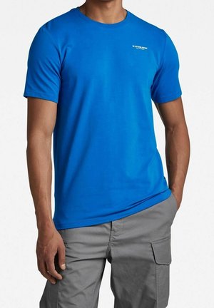 Jasnoniebieski T-shirt z krótkim rękawem, wykonany z gładkiej bawełnianej tkaniny, z okrągłym dekoltem i małym logo na górnej lewej części klatki piersiowej.