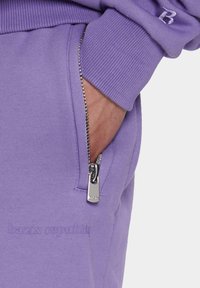Lilla sweatshirt med en lynlåslomme med metal hardware, ribbede manchetter og prægede logo detaljer. Blød stofstruktur.