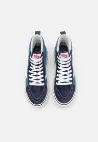 Marineblå og teal høy-top sneakers med semsket skinn og mesh-materialer, hvite lisser og merket tungelapp. Har detalj med hvit side stripe.