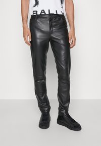 Svarta läderbyxor med slim fit, med dragkedja framtill, fickor och en slät textur. Matchas med svarta högklackade sneakers.