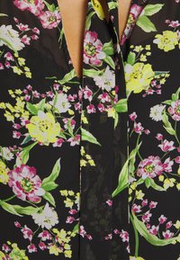 Blomstret stof med pink, gule og hvide blomster på en sort baggrund. Gennemsigtigt materiale med dyb V-udskæring og båndbind.