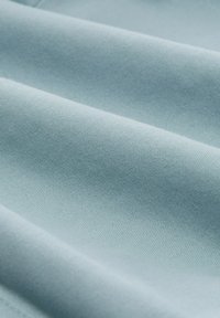 Țesătură de culoare albastru deschis, cu o textură netedă și moale, având o țesătură ușor riglata, ce evidențiază pliuri delicate și o culoare uniformă în întregime.