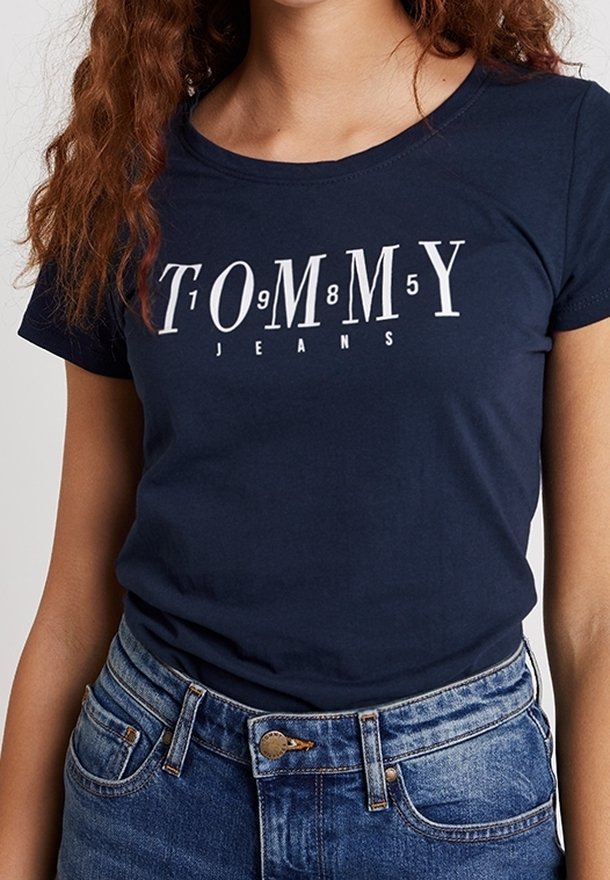Marinblå bomull T-shirt med vit "TOMMY JEANS" tryck med numeriska accenter. Slim fit, korta ärmar och rund halsringning.