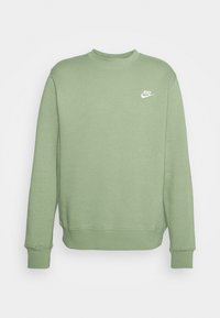 Grön bomullströja med rund halsringning och långa ärmar, samt ribbade muddar. Har en liten vit Nike-logotyp på vänster bröstområde.