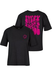 Černé tričko s krátkým rukávem, na kterém se nachází růžový grafický design se textem "VŠE JE HEZKÉ" na zádech a malým růžovým logem na přední části.