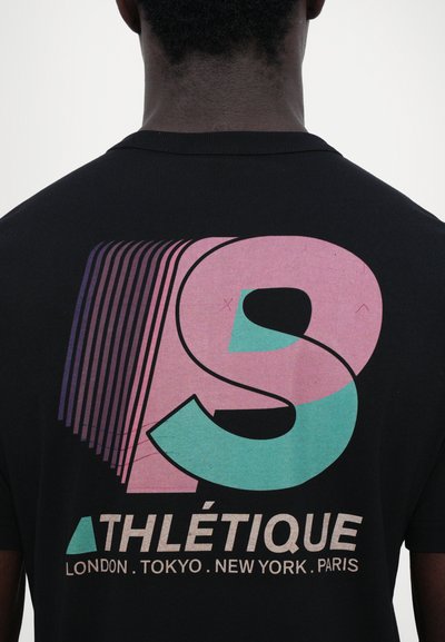Black t-shirt featuring a large graphic with layered 'S' in pink and teal, and the word "ATHLÉTIQUE" above city names in beige.