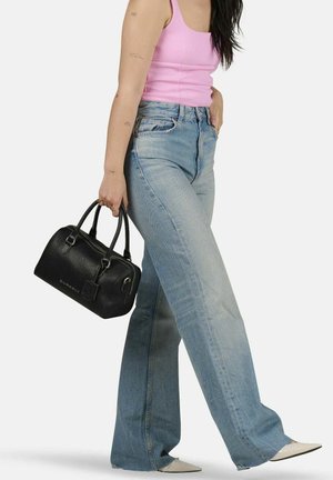 Borsa a mano nera in pelle con superficie testurizzata e doppi manici. Indossata con jeans a zampa d'elefante azzurri chiari e un top aderente rosa.