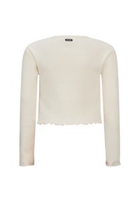 Cremefarbenes, geripptes Langarm-Crop-Top mit gewelltem Saum und subtiler Textur. Mit einem Etikett namens "RETOUR" in der Nähe des Ausschnitts.