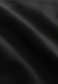 Czarna tkanina o gładkiej fakturze, z delikatnymi prążkami i lekkim połyskiem, ułożona tak, aby ukazać fałdy i krzywizny.