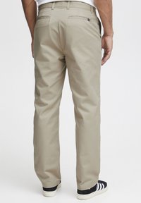 Beige chinos with a straight-leg design, made from cotton. Features two back pockets and a subtle logo on the waistband.