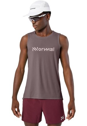 Männlicher Athlet trägt ein ärmelloses graues Oberteil, bordeauxrote Shorts, weiße Mütze und Sportsonnenbrille, schaut seitlich vor weißem Hintergrund.