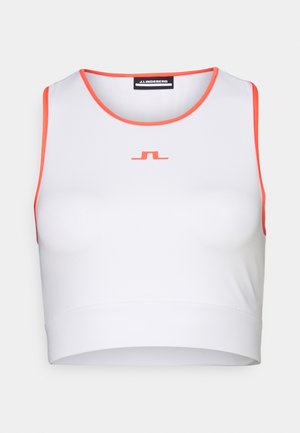 Valkoinen urheilullinen crop-top oransseilla yksityiskohdilla, pyöreällä kaula-aukolla ja minimalistisella logolla edessä. Sileä kangastuntu.