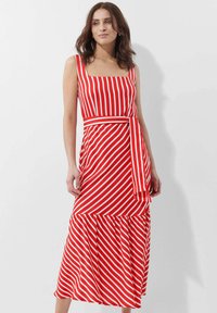Maxikleid mit rot-weißem Streifenmuster, quadratischem Ausschnitt, ärmellosem Design und einem gebundenen Stoffgürtel. Es hat einen weit ausladenden, Rüschensaum.