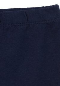 Tejido de algodón azul marino con una textura suave y cintura elástica, que presenta costuras ordenadas a lo largo del borde superior y sin patrones visibles.