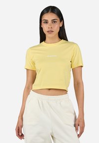 Tricou scurt galben din bumbac, cu guler rotund, m�âneci scurte și un mic logo alb pe piept. Textură moale.