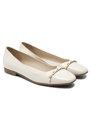 Białe skórzane baleriny z błyszczącym, spiczastym noskiem, płaską brązową podeszwą i dekoracyjnym złotym łańcuszkiem na wierzchu.