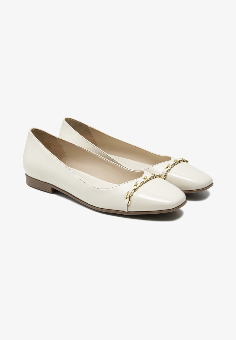 Ballerines blanches en cuir avec un bout pointu brillant, une semelle plate brune et un accent décoratif en chaîne dorée sur le devant.