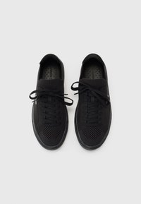 Sneaker nere con parte superiore in maglia, lacci piatti e suole in gomma testurizzata. Presentano dettagli in rete per la traspirabilità e un design elegante.