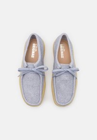 Šedé skládací boty s kulatou špičkou, světle modré tkaničky a gumovou podrážkou. Texturovaný svršek a měkké vnitřní podšívka. Viditelná značka uvnitř.